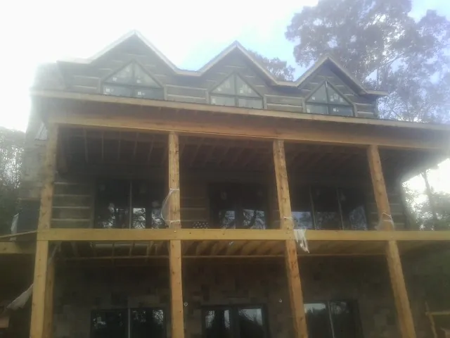 Dormers and porch framing on a large log home under construction — Roof Coating work by our crew in Evangeline