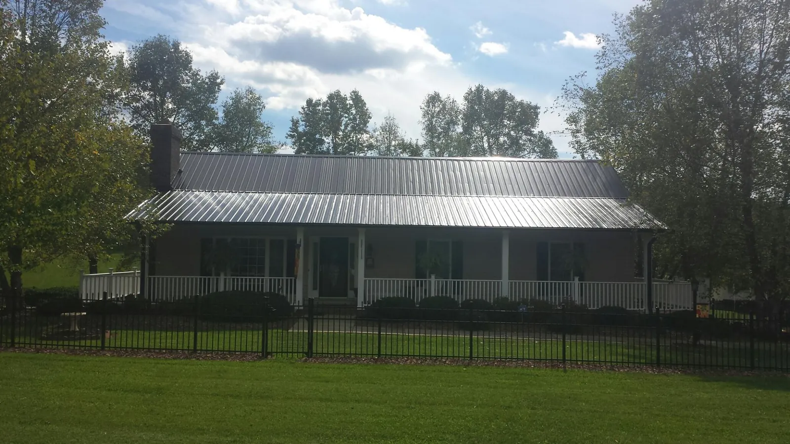 Gray metal roof on a brick ranch with a full width front porch — Gutter Guard Installation work by our crew in Evangeline